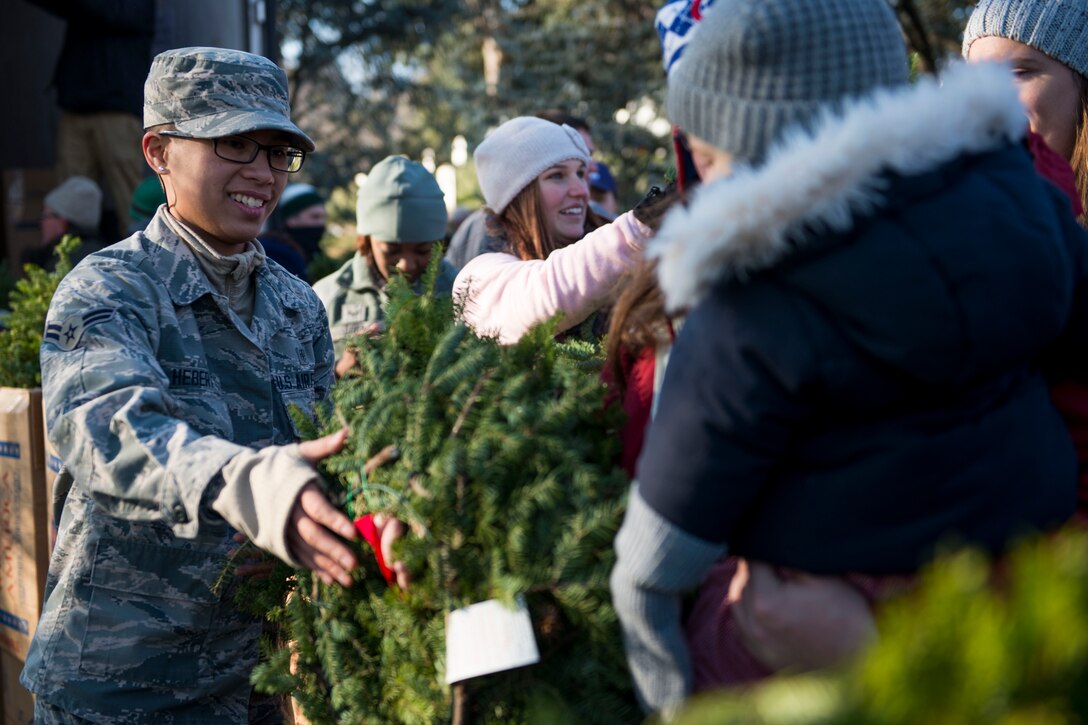 An airman passes out wreaths to a line of people.