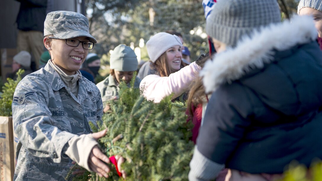 An airman passes out wreaths to a line of people.