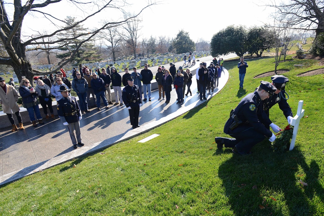 Two police officers place a wreath at a grave marker.