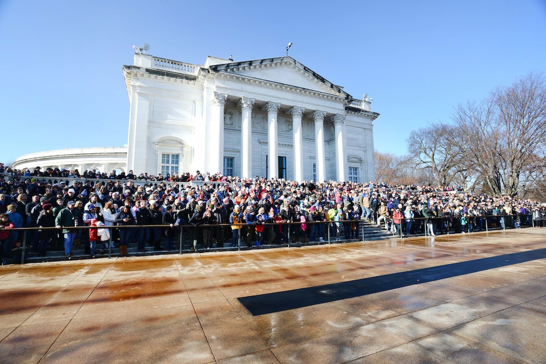 A crowd stands on steps in front of a building.