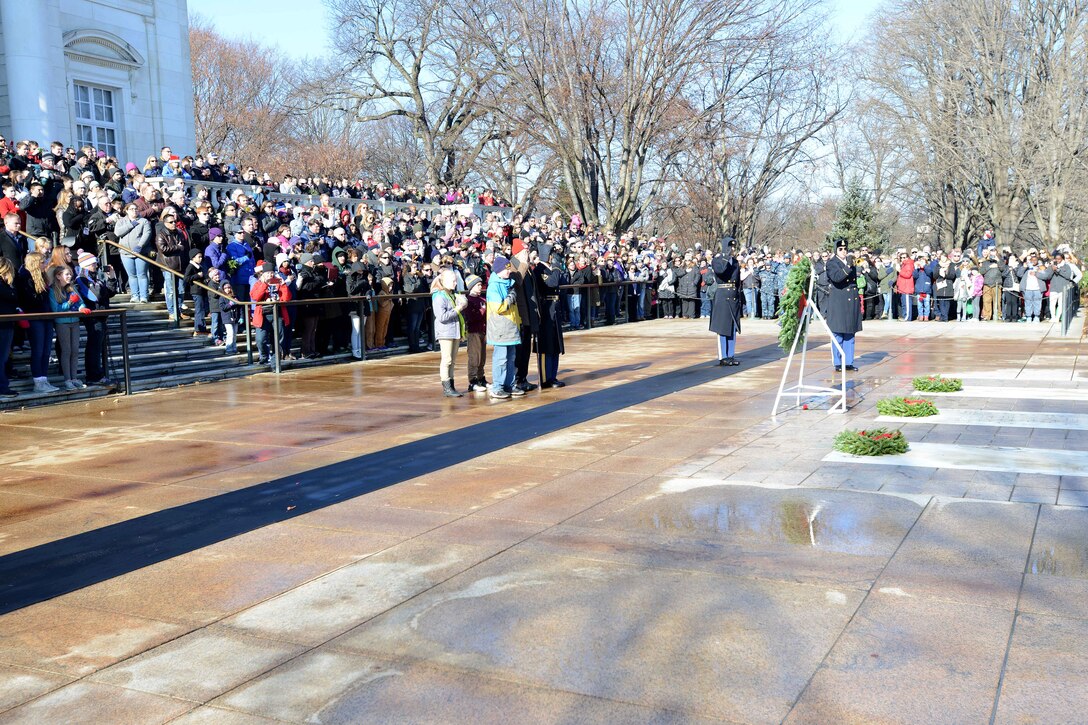 A soldier and civilians salute and place their had over their hearts.