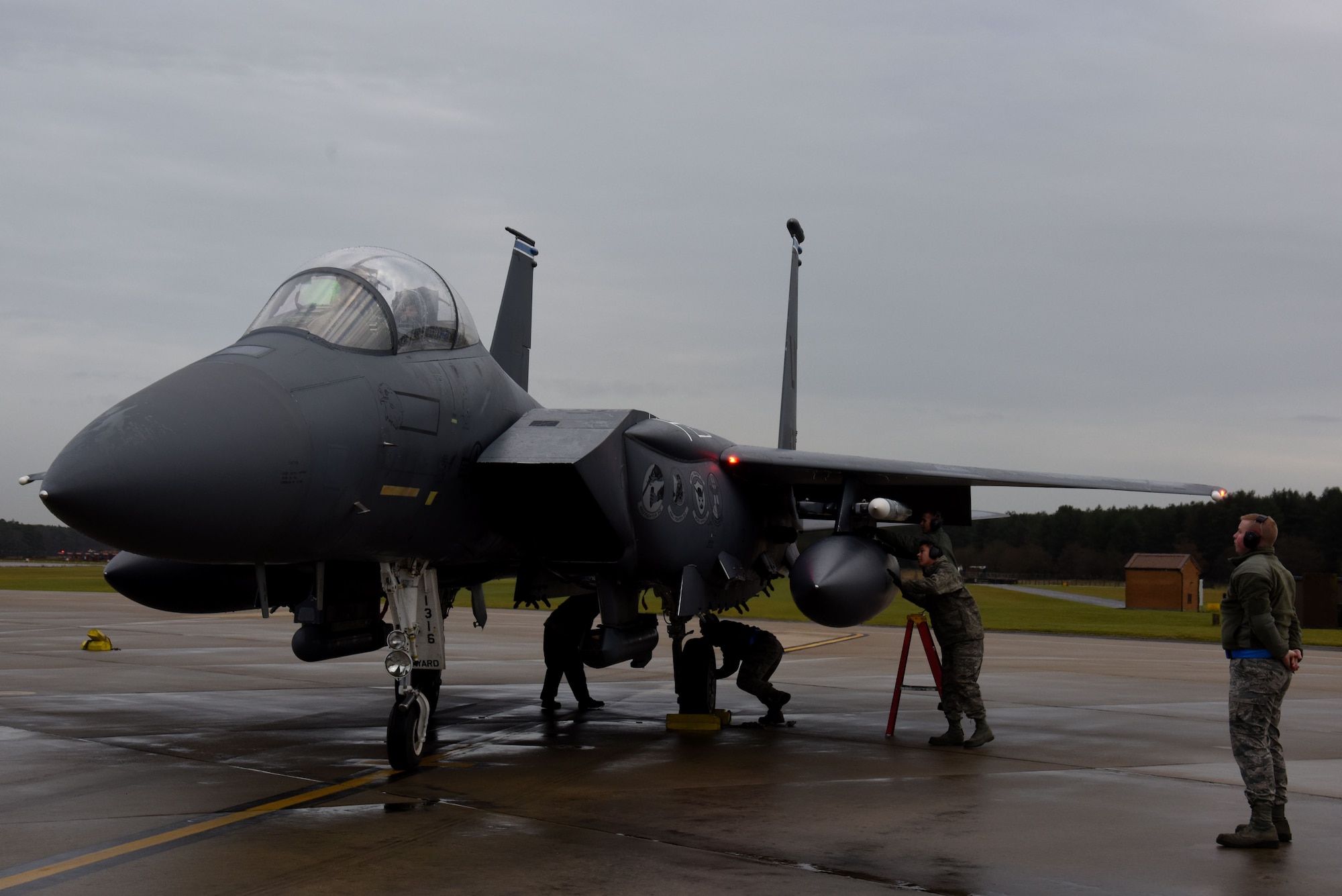 A 48th Aircraft Maintenance Squadron crew chief waits to marshal an F-15E Strike Eagle after its end-of-runway inspection at Royal Air Force Lakenheath, England, Dec. 13. Each EOR team is comprised of two crew chiefs, two weapons load crew members and a noncommissioned officer overseeing the process. (U.S. Air Force photo/Senior Airman Abby L. Finkel)