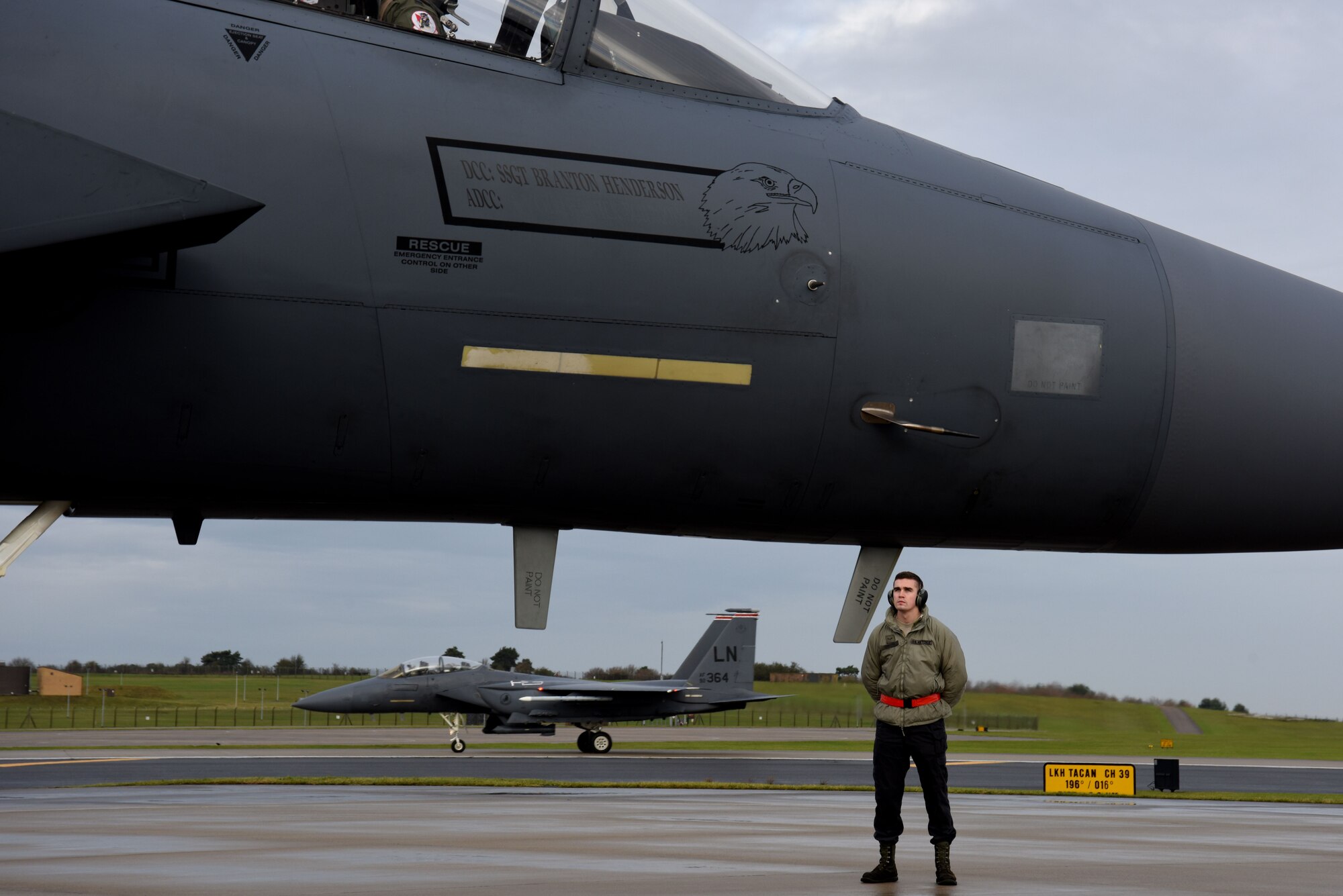 A 48th Aircraft Maintenance Squadron crew chief waits to marshal an F-15E Strike Eagle after its end-of-runway inspection at Royal Air Force Lakenheath, England, Dec. 13. Each EOR team is comprised of two crew chiefs, two weapons load crew members and a noncommissioned officer overseeing the process. (U.S. Air Force photo/Senior Airman Abby L. Finkel)