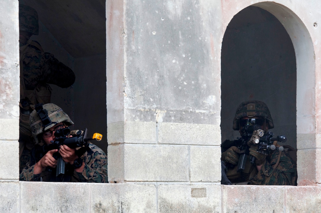 Marines provide security in two windows during a motorized raid as a part of an exercise.