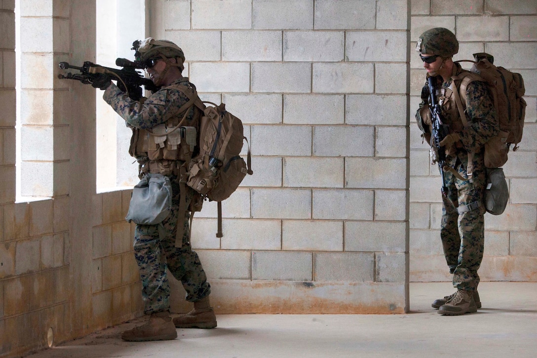 Two Marines provide security from a building.