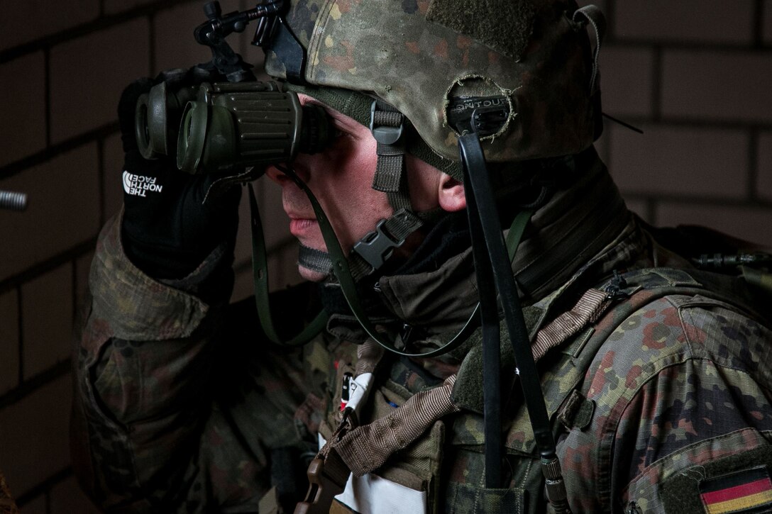 A German soldier looks for potential enemies through binoculars.