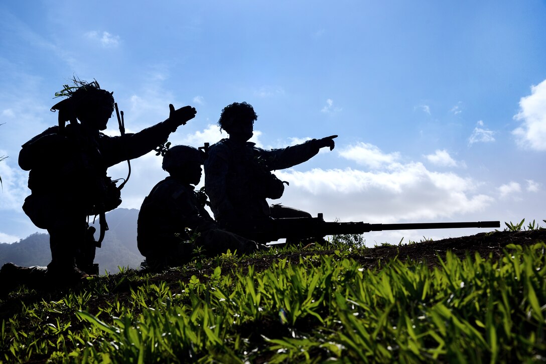 Three soldiers are silhouetted against a blue sky.