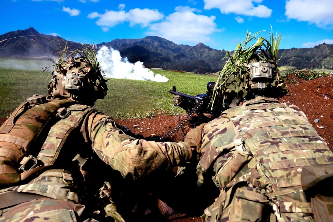 Soldiers lay on the ground behind a pile of dirt.