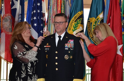 Phyllis Perdue (left) and Linda Boruff (right) add shoulder boards reflecting the new rank of Brig. Gen. Bill Boruff during a promotion ceremony Dec. 15 in San Antonio. Linda is the wife of the commanding general for the Mission and Installation Contracting Command and Perdue is his sister.