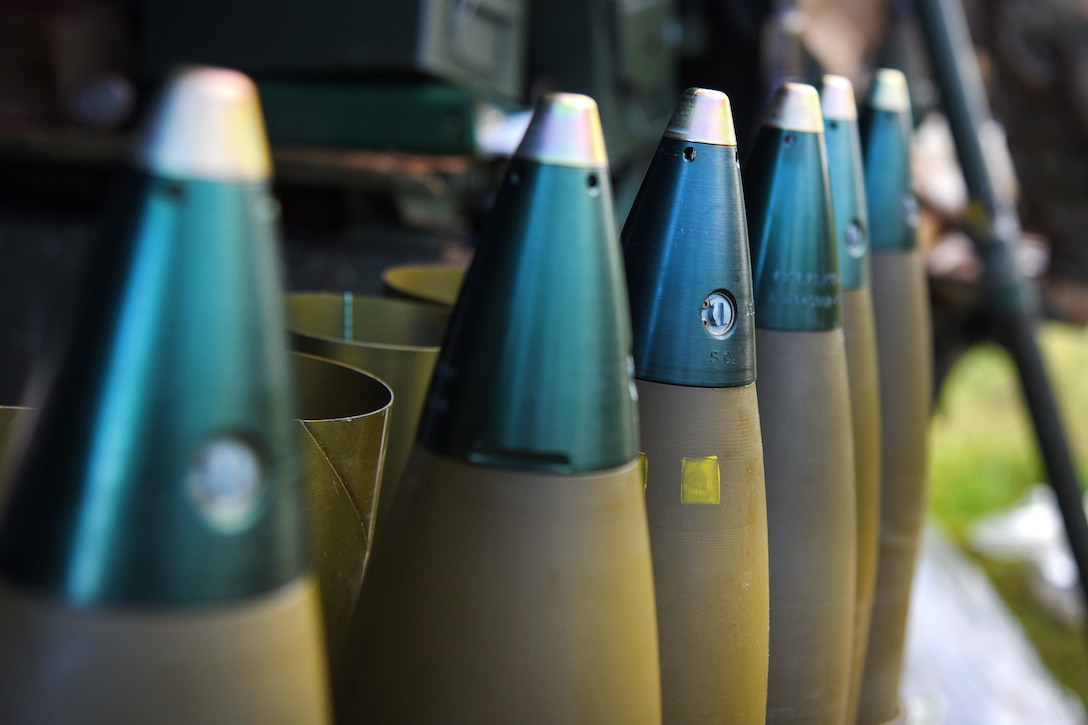 Howitzer rounds sit on the ground in a row.