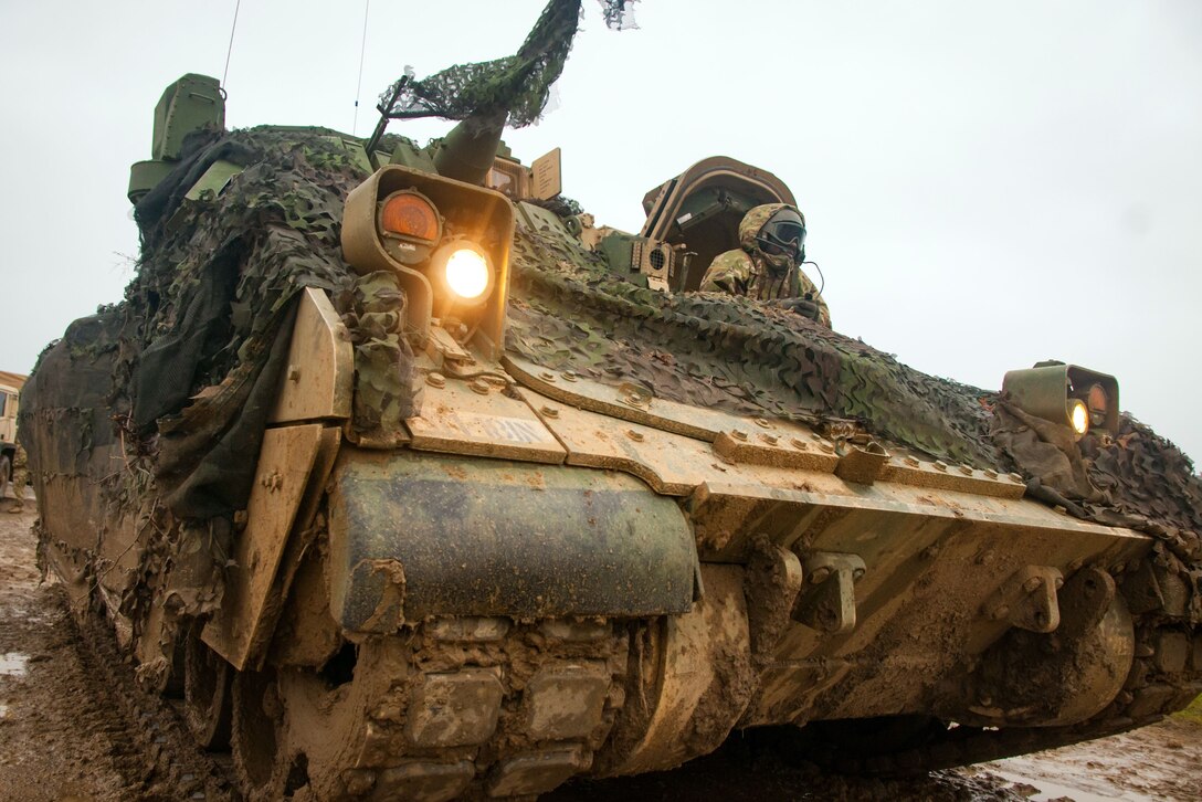Soldiers position a tank in a staging area.