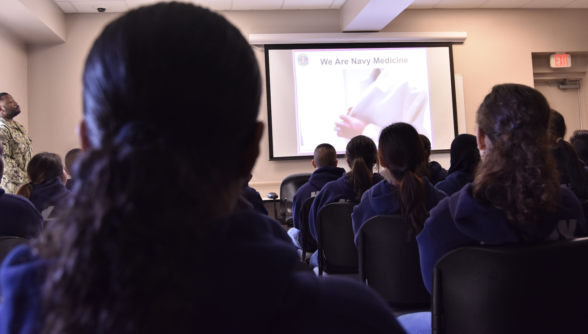 Navy Junior Reserve Officer Training Corps (NJROTC) cadets from George Bush High School near Houston, Texas, receive a Navy Medicine overview presentation from Lt. Cmdr. Sarah Gentry. Forty-two students visited Navy Medicine Training Support Center (NMTSC) in San Antonio, Texas, to receive a basic orientation to the Navy and to represent the more than 200-member George Bush High School NJROTC unit in the Sea Dragon Classic Drill Meet at Southwest High School in San Antonio.