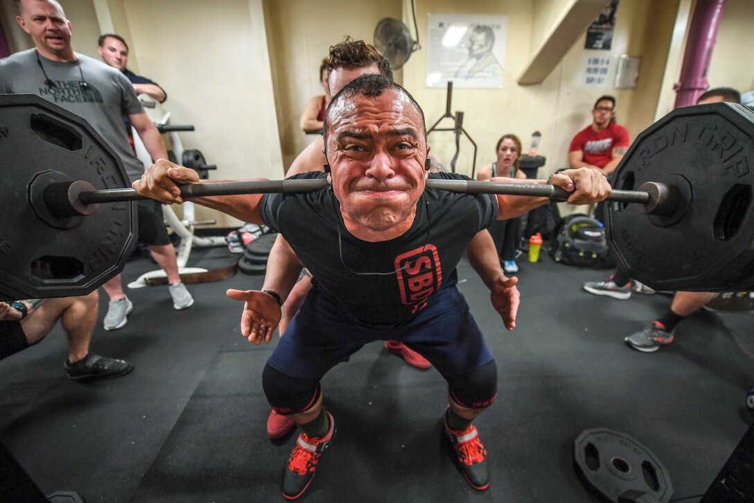 A weightlifter strains to lift a barbell