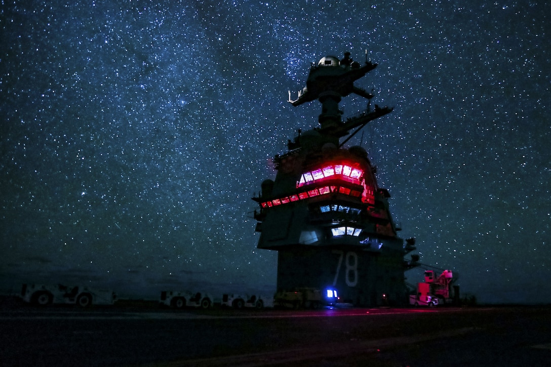 An aircraft carrier transits the Atlantic Ocean at night.