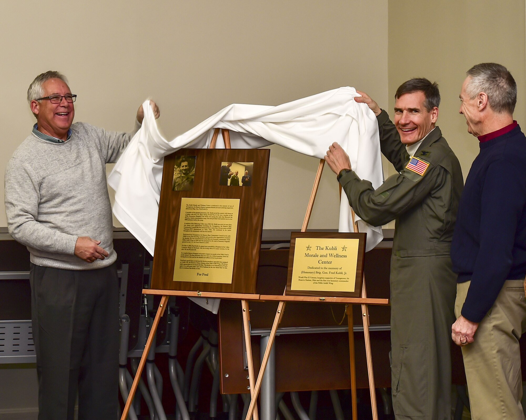 Col. Dan Sarachene, 910th Airlift Wing commander, and Lt. Col. Bart Elsea, 910th Airlift Wing Operations Group commander, listen as David Kubli, son of Fred Jr. and Laverne Kubli, gives remarks during a building dedication ceremony honoring Fred here, Dec. 15, 2017.