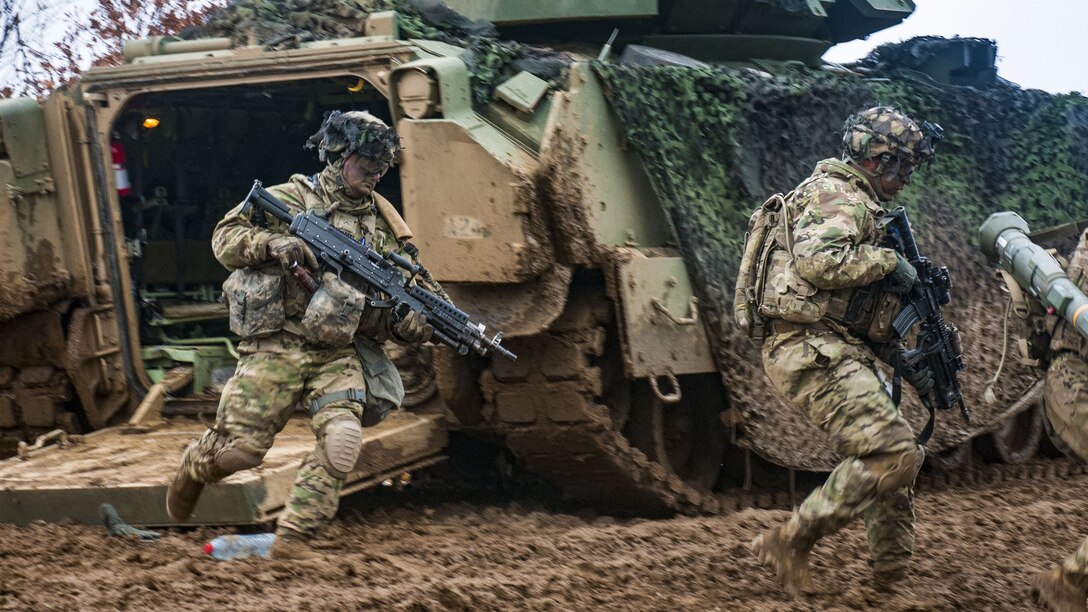 Two soldiers dismount a M2 Bradley.