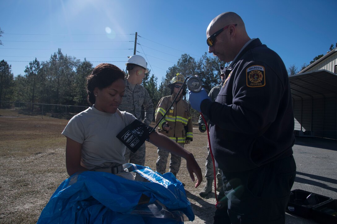 A Valdosta Fire Department paramedic takes the vitals of Airman 1st Class Briana Mciver, 23d Bioenvironmental Engineering Flight apprentice, before she dons chemical protective gear, Dec. 13, 2017, in Valdosta, Ga. Fire departments from Lowndes County, Valdosta, Tifton and Albany, the 23d Civil Engineer Squadron’s Fire Department and Emergency Management Flights, and 23d Medical Group Bioenvironmental Engineering Flight responded to the aftermath of a simulated tornado hitting the Du Pont Crop Protection factory. (U.S. Air Force photo by Staff Sgt. Eric Summers Jr.)