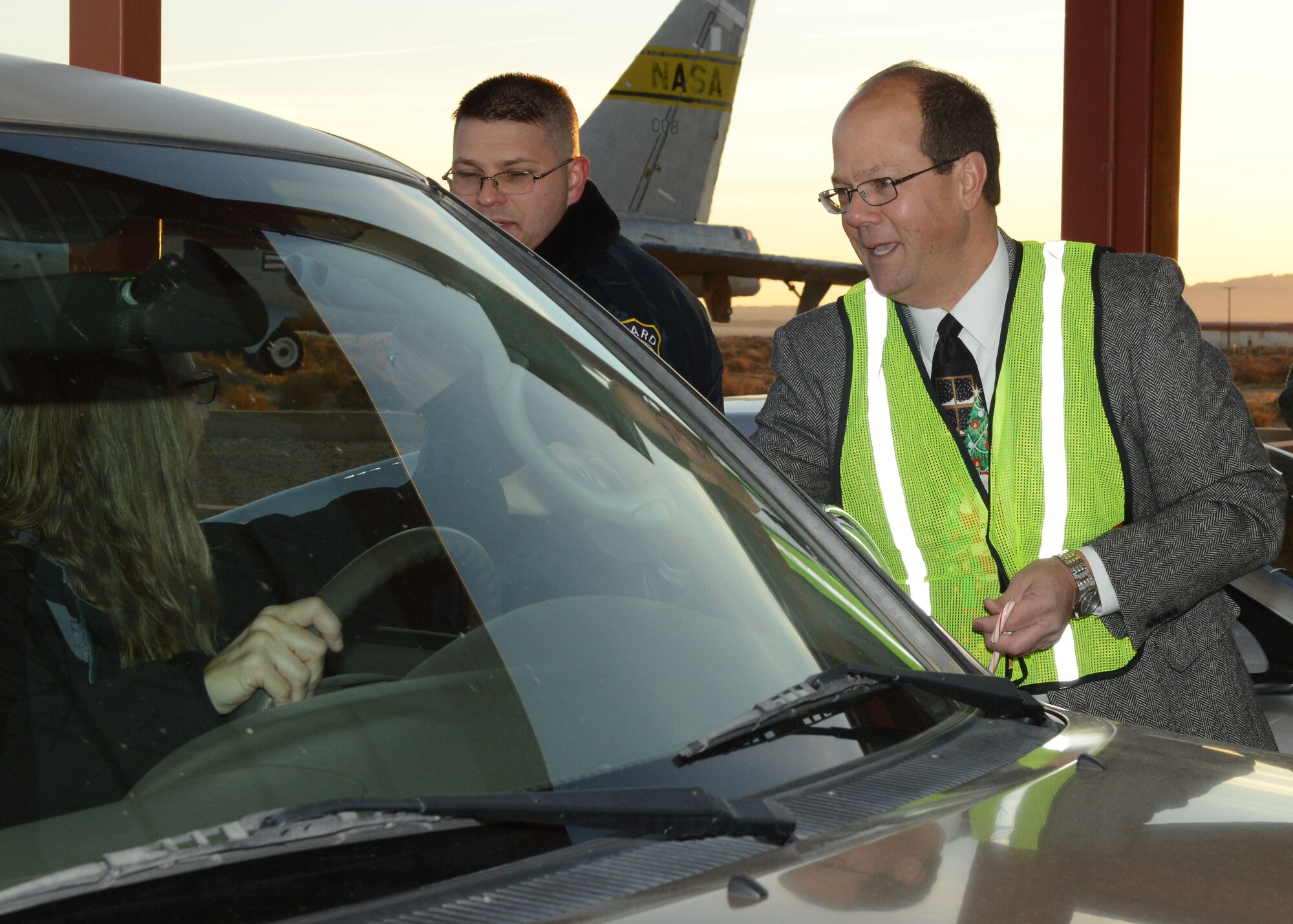 Col. Matthew Higer, U.S. Air Force Test Pilot School commandant, hands a candy cane and holiday card to a motorist at Edwards AFB’s North Gate Dec. 18. The colonel teamed up with Airman 1st Class Jerome Holliday, 412th Security Forces Squadron, for the morning. (U.S. Air Force photo by Kenji Thuloweit)