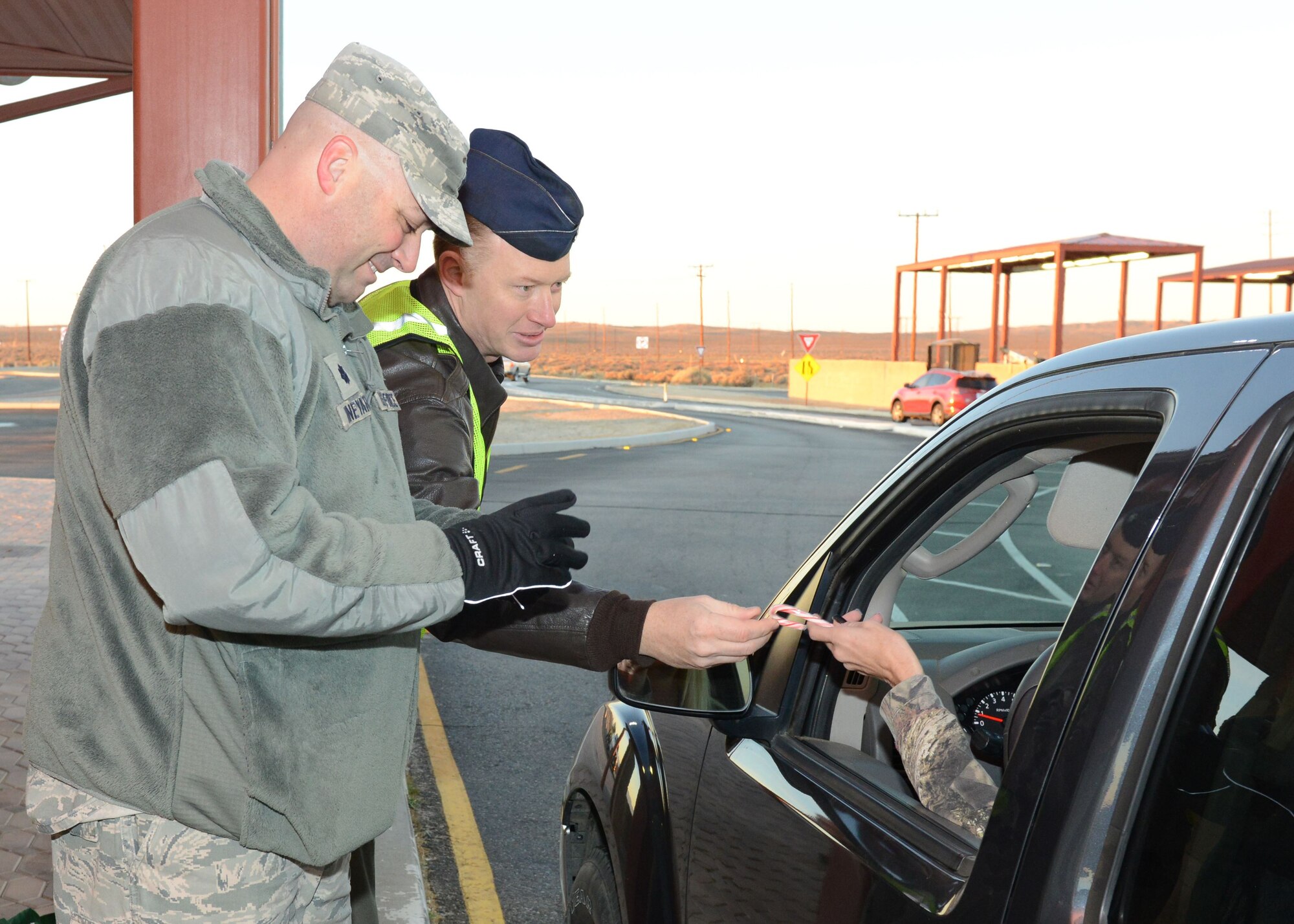 Lt. Col. Grant Vineyard, 412th Mission Support Group (left), and Lt. Col. Cory Naddy, 412th Test Wing Safety Office, greet motorists at the North Gate Dec. 18. A yearly tradition, base leadership and supervisors hand out candy canes and holiday cards at all of Edwards AFB’s entry gates to show their appreciation to the Edwards workforce and wish everyone a safe holiday season. (U.S. Air Force photo by Kenji Thuloweit)