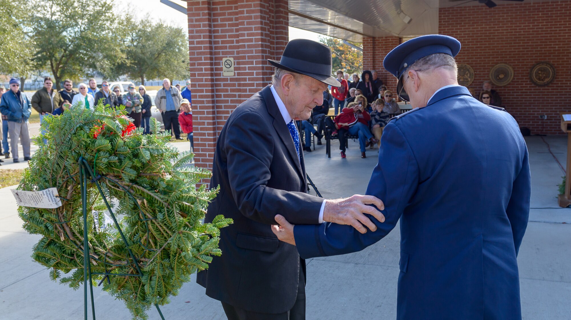 Col. David “Hank” Rogers, Civil Air Patrol commander, assists Victor Mavar, U.S. Merchant Marine and Korean War veteran, during the Wreaths Across America ceremony at the Biloxi National Cemetery Dec. 16, 2017, in Biloxi, Mississippi. Wreaths Across America, a non-profit organization, was formed as an extension of the Arlington Wreath Project. The Arlington Wreath program was started by Morrill Worcester in 1992 with the donation and laying of 5000 Christmas wreaths to Arlington National Cemetery. (U.S. Air Force photo by André Askew)
