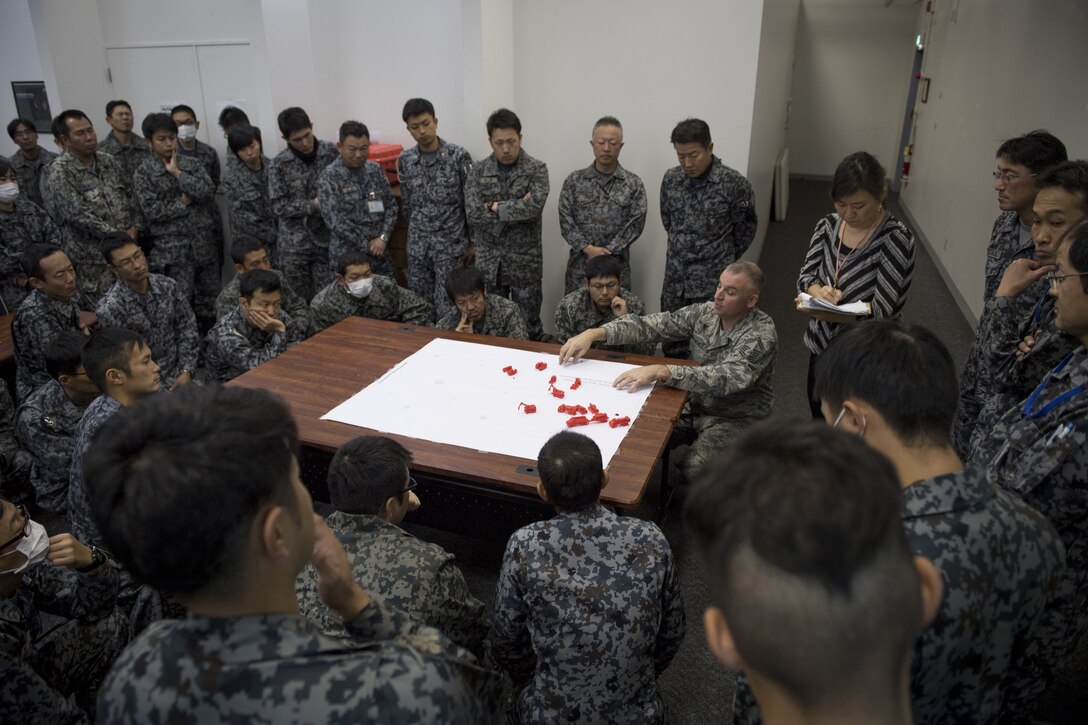 U.S. Air Force Senior Master Sgt. Alexander B. Benedict, 374th Civil Engineer Squadron heavy repair superintendent, conducts a rapid airfield damage repair table-top briefing with Koku Jietai (Japan Air Self-Defense Force) engineers, Dec. 12, 2017, at Yokota Air Base, Japan.