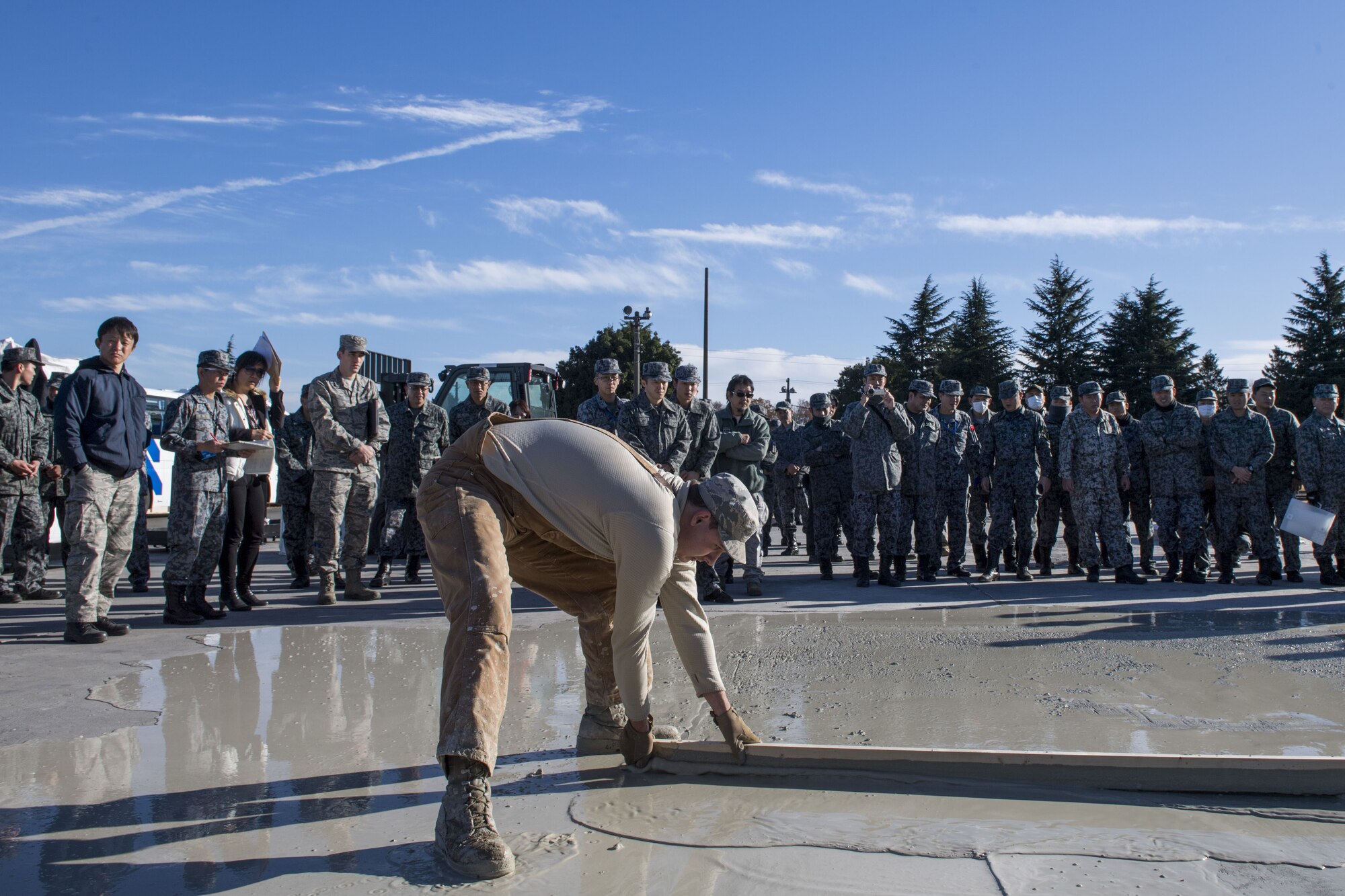 A U.S. Air Force Airman with the 374th Civil Engineer Squadron levels off a newly poured concrete pad during a rapid airfield damage repair demonstration, Dec. 12, 2017, at Yokota Air Base, Japan.