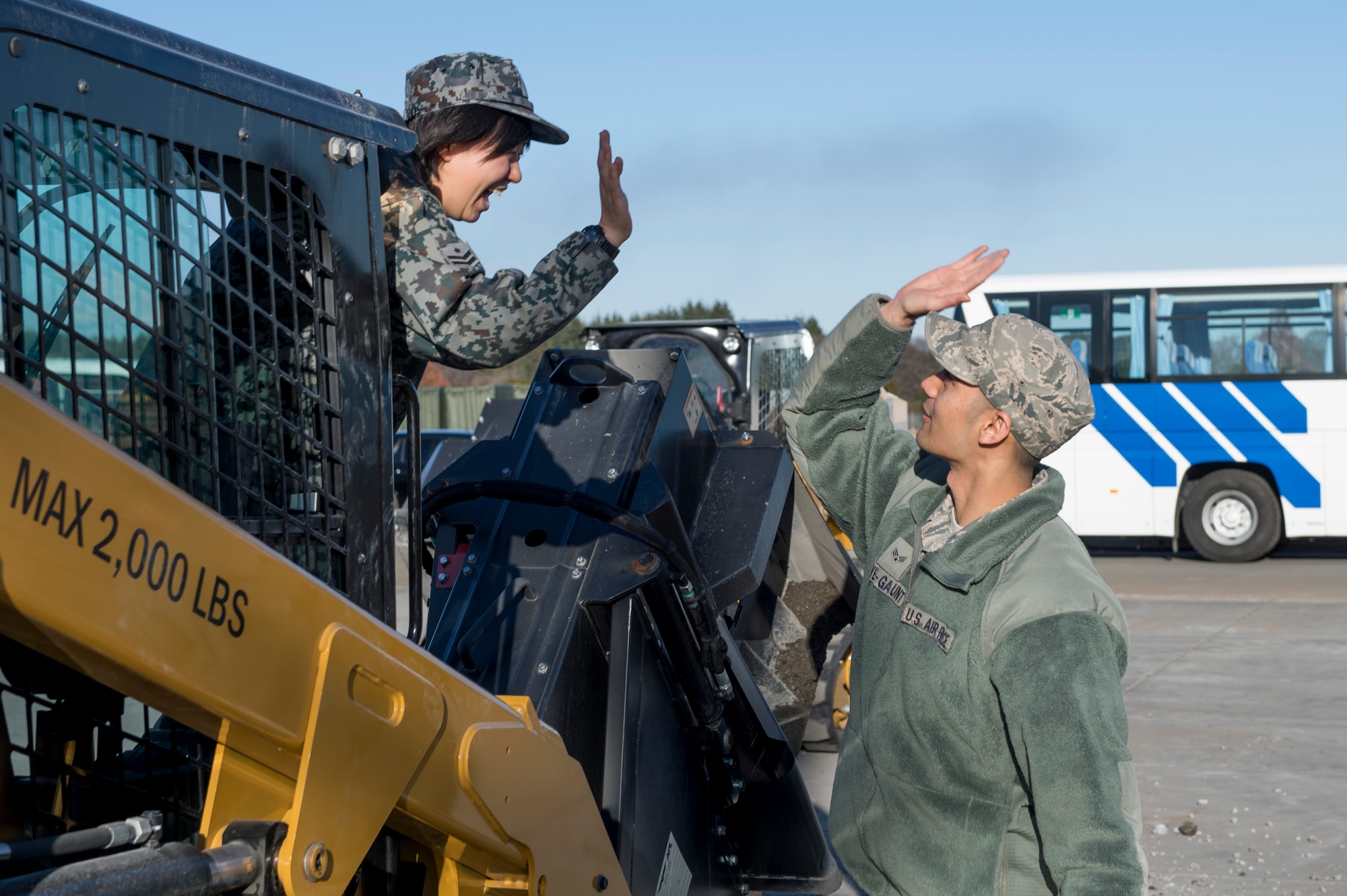 A U.S. Air Force Airman with the 374th Civil Engineer Squadron give a high-five to a Koku Jietai (Japan Air Self-Defense Force) engineer after operating equipment during a rapid airfield damage repair demonstration, Dec. 12, 2017, at Yokota Air Base, Japan.
