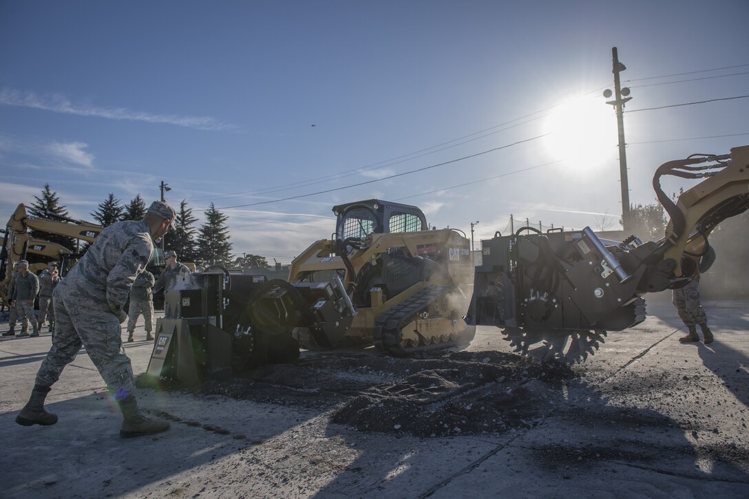U.S. Air Force Airman with the 374th Civil Engineer Squadron guide Koku Jietai (Japan Air Self-Defense Force) engineers operating equipment to cut concrete during a rapid airfield damage repair demonstration, Dec. 12, 2017, at Yokota Air Base, Japan.