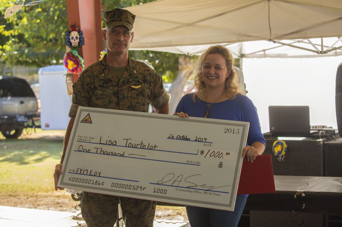 Lisa Tourtelot, the Marine Corps Air Station (MCAS) Yuma Office of Communication assistant (right) is presented the MCAS Yuma 2017 Employee of the Year award by U.S. Marine Corps Col. David A. Suggs, the station’s commanding officer (left) at the MCAS Yuma, Ariz., Picnic Pavilion, Oct. 26, 2017. Each quarter, a civilian employee is recognized as the Employee of the Quarter and at the end of the fiscal year, one employee is recognized as the Employee of the Year.