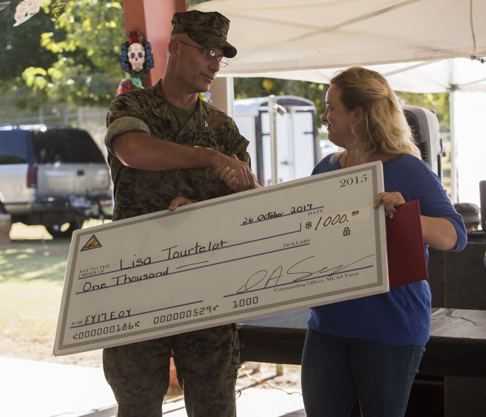 Lisa Tourtelot, the Marine Corps Air Station (MCAS) Yuma Office of Communication assistant (right) is presented the MCAS Yuma 2017 Employee of the Year award by U.S. Marine Corps Col. David A. Suggs, the station’s commanding officer (left) at the MCAS Yuma, Ariz., Picnic Pavilion, Oct. 26, 2017. Each quarter, a civilian employee is recognized as the Employee of the Quarter and at the end of the fiscal year, one employee is recognized as the Employee of the Year.
