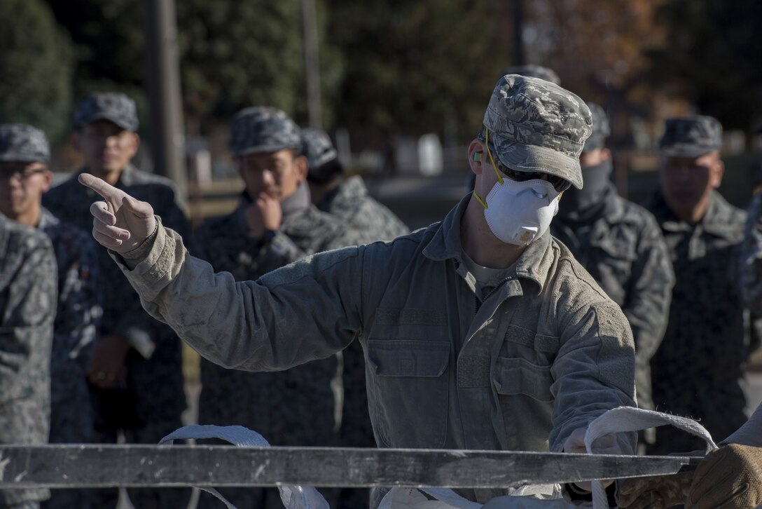 A U.S. Air Force Airman with the 374th Civil Engineer Squadron gives commands to a forklift operator during a rapid airfield damage repair demonstration, Dec. 12, 2017, at Yokota Air Base, Japan.