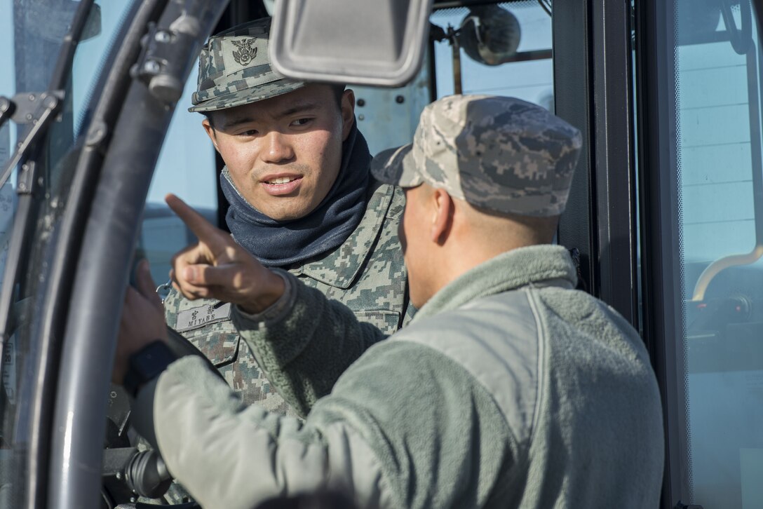 A U.S. Air Force Airman with the 374th Civil Engineer Squadron teaches a Koku Jietai (Japan Air Self-Defense Force) engineer how to operate a piece of equipment during a rapid airfield damage repair demonstration, Dec. 12, 2017, at Yokota Air Base, Japan.