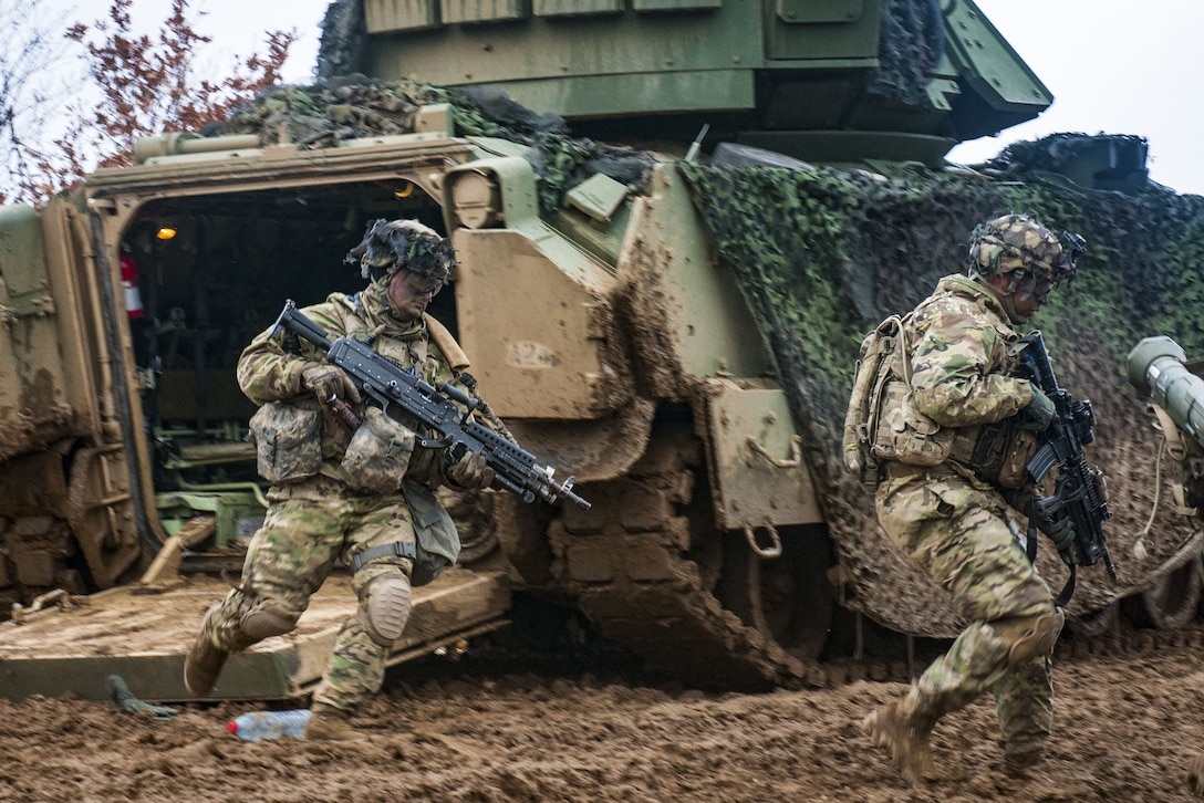 Two soldiers dismount a M2 Bradley.