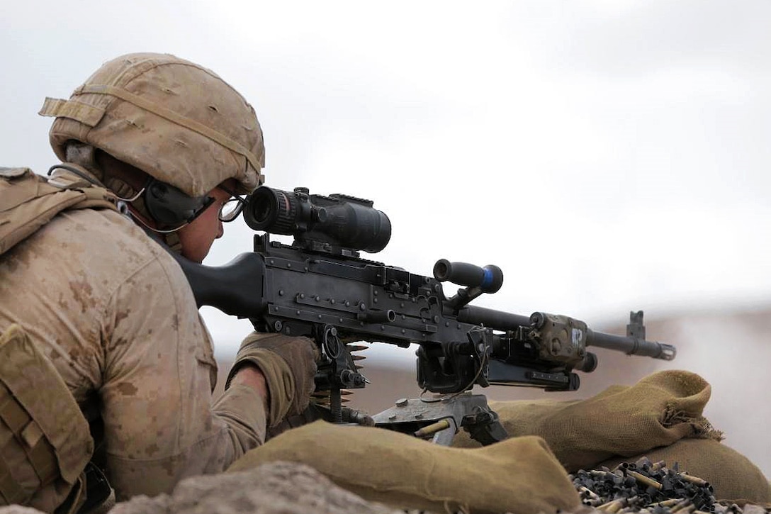 A Marine lays against dirt to fire a weapon.