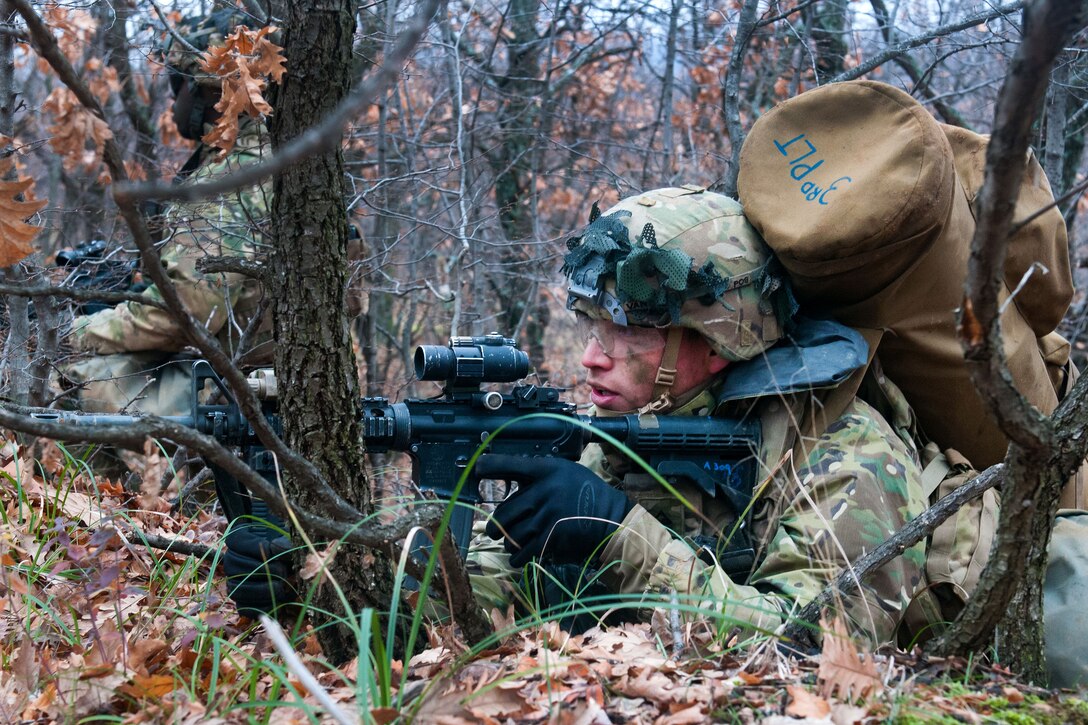 A soldier scans his sector while providing security in the wood lines during live-fire.