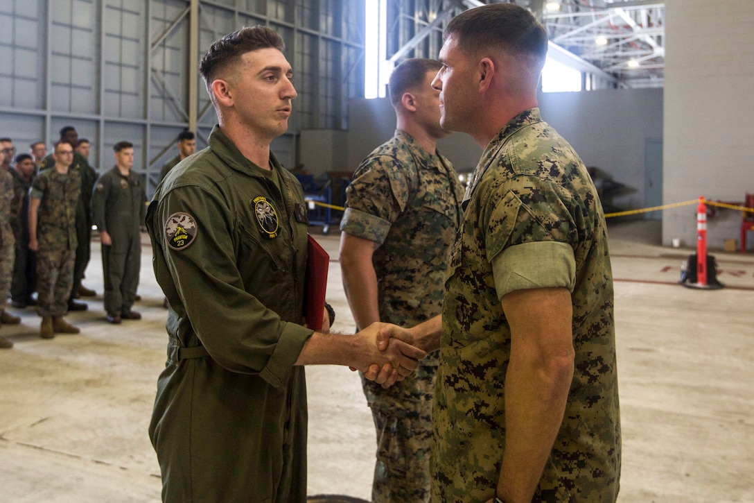 Sgt. Joseph Latsch, an unmanned aerial system UAS operator with Marine Unmanned Aerial Vehicle Squadron 3 VMU-3, shakes hands with Lt. Col. Kenneth Phelps, the commanding officer of VMU-3, after receiving an award during a ceremony at Hangar 103, Marine Corps Air Station Kaneohe Bay, Dec. 11, 2017. Latsch was awarded the Navy and Marine Corps Achievement Medal with the newly authorized Remote Impact “R” Device alongside Sgt. Ethan Mintus, a fellow UAS operator with VMU-3, for their performance during combat operations.