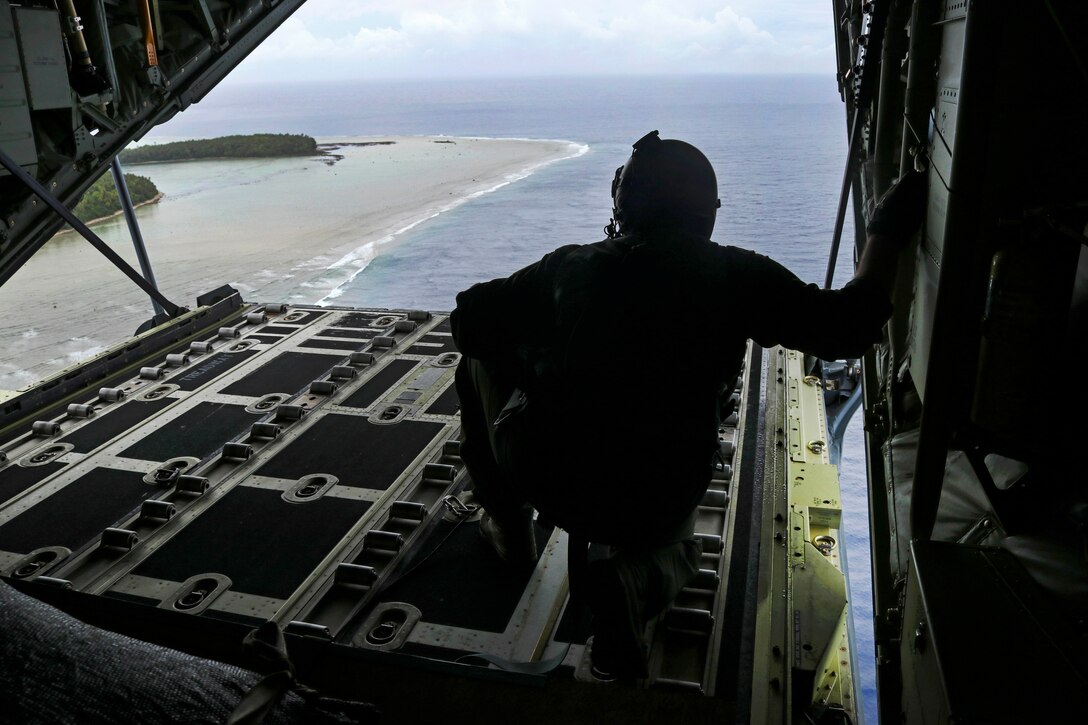 An airman looks out the back of a C-130J Super Hercules while passing the Federated States of Micronesia.