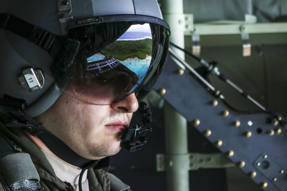 An airman looks toward an island, which is reflected in his mask.