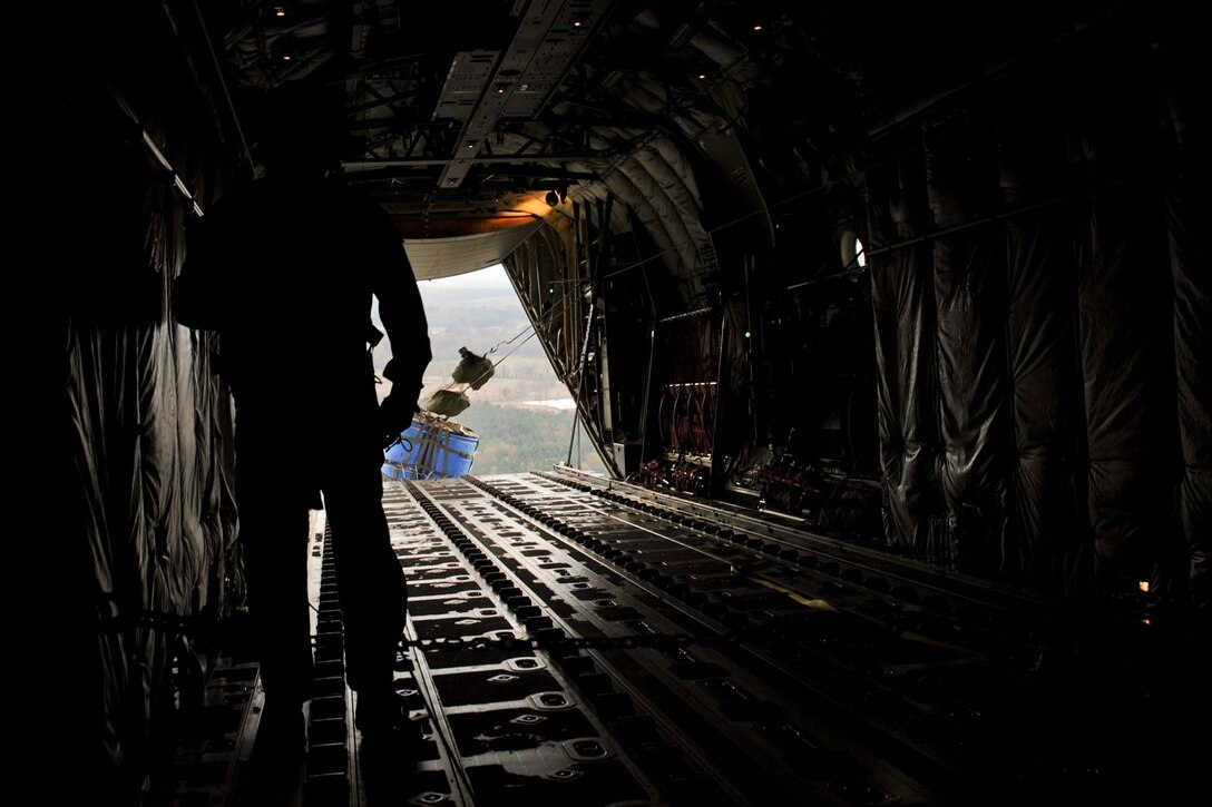A U.S. Air Force loadmaster watches as a water barrel container delivery system (CDS) bundle exits the back of a C-130J Super Hercules during a training sortie Nov. 21, 2017, near an airfield in Hope, Arkansas.