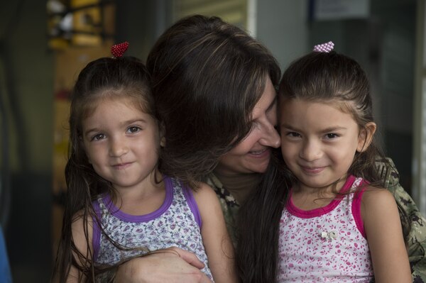 A Navy doctor poses with two smiling Brazilian girls.