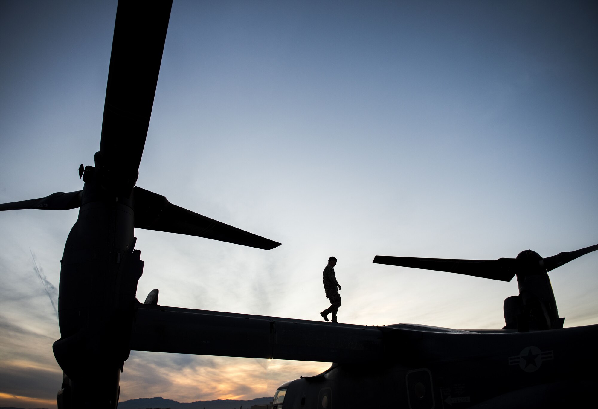 An Airman assigned to the 14th Weapons Squadron at Hurlburt Field, Florida, walks on a CV-22 Osprey helicopter prior to a training mission for the United States Air Force Weapons School (USAFWS) at Nellis Air Force Base, Nevada, Dec. 10, 2017. At the conclusion of nearly 400 hours of graduate-level academics and combat training missions, the USAFWS course climaxes with a weeklong exercise, known as Weapons School Integration. (U.S. Air Force photo by Senior Airman Kevin Tanenbaum/Released)