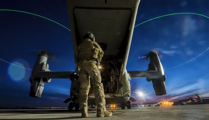 An Airman assigned to the 14th Weapons Squadron at Hurlburt Field, Florida, stands outside of a CV-22 Osprey helicopter before a night mission for the United States Air Force Weapons School advanced integration at Nellis Air Force Base, Nevada, Dec. 10, 2017. The CV-22 Osprey is a tiltrotor aircraft that possesses the vertical takeoff, hover and vertical landing qualities of a helicopter to conduct long-range infiltration, exfiltration and resupply missions for special operations forces. (U.S. Air Force photo by Senior Airman Kevin Tanenbaum/Released)