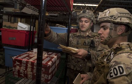Staff Sgt. Kyle Bushy, left, 628th Civil Engineer Squadron Explosive Ordnance Disposal technician and Staff Sgt. Sherwood D.Johnson,628th CES EOD technician inspect a suspect package before performing hook and line techniques to safely move it during the EOD Olympics Dec. 15, 2017.