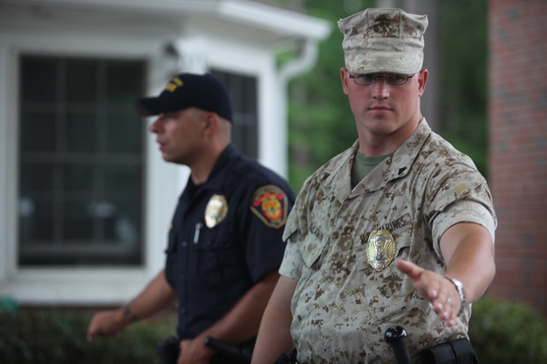 U.S. Marine Corps Cpl. James Willaman, front, and Tony Brienza, military and civilian patrol officers with 1st Platoon, Provost Marshal?s Office, give the signal for vehicles to halt at the main entry gate in Marine Corps Base Camp Lejeune, N.C., May 17, 2010. Military Police and Marine Corps Civilian Law Enforcement Program personnel protect service members, their families and Department of Defense civilians who live and work inside the base. (U.S. Marine Corps photo by Cpl. Jo Jones/Released)
