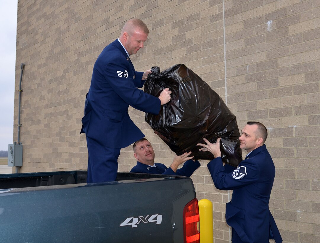 Staff Sgt. Bryan Parker, 87th Aerial Port Squadron, receives a bag of toys to load in a pickup truck from fellow squadron Airmen Master Sgts. Paul Errett, middle, and Brian Anders, right, Dec. 15, 2017.