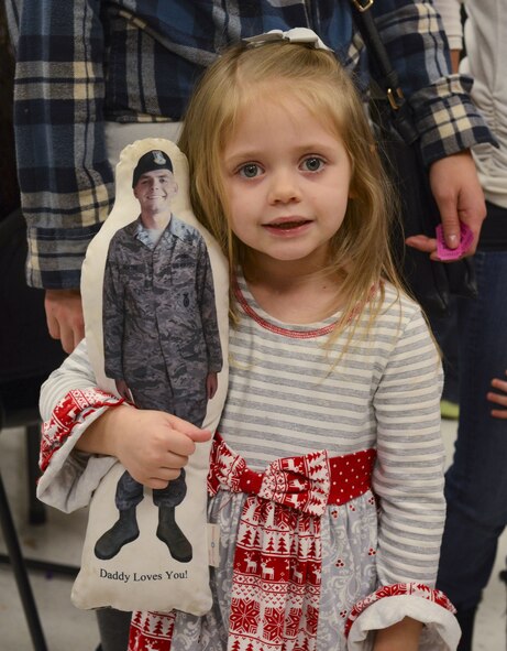 Adalyn Deryke, daughter of Brandon Deryke, 822d Base Defense Squadron NCO in charge of combat arms, poses for a photo during a holiday party with a pillow displaying her father’s picture, Dec. 15, 2017, at Moody Air Force Base, Ga. The Airman and Family Readiness Center hosted the event for families of deployed or remote-tour Airmen, and families enrolled in the Exceptional Family Member Program. During the party, families enjoyed a turkey dinner, played games, made arts and crafts for their loved ones and shared a special moment with Santa Claus. (U.S. Air Force photo by Senior Airman Lauren M. Sprunk)