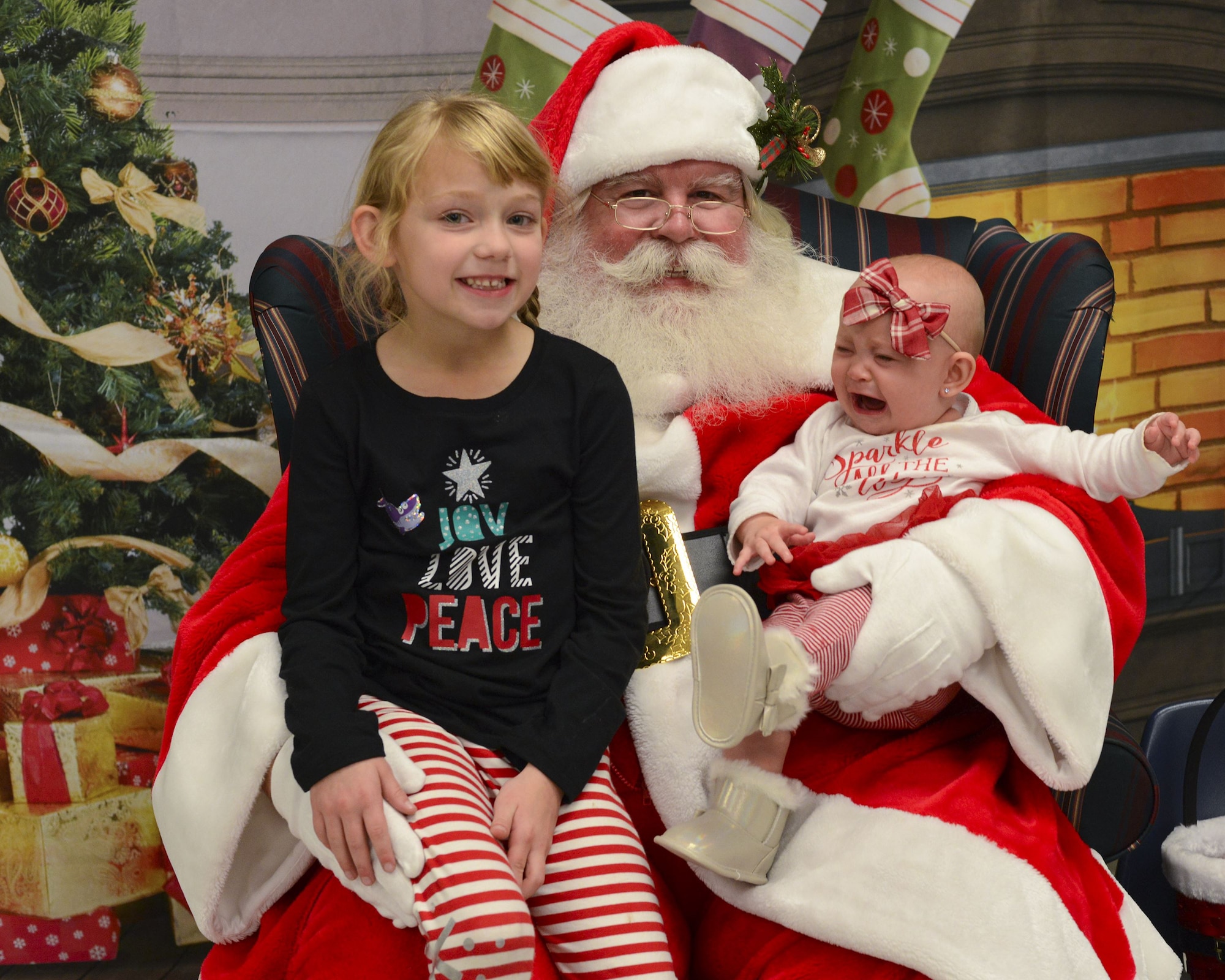 Reagan and Meredith, daughters of Senior Airman Michael Verheyden, 74th Aircraft Maintenance Unit crew chief, pose for a photo with Santa during a holiday party, Dec. 15, 2017, at Moody Air Force Base, Ga. The Airman and Family Readiness Center hosted the event for families of deployed or remote-tour Airmen, and families enrolled in the Exceptional Family Member Program. During the party, families enjoyed a turkey dinner, played games, made arts and crafts for their loved ones and shared a special moment with Santa Claus. (U.S. Air Force photo by Senior Airman Lauren M. Sprunk)
