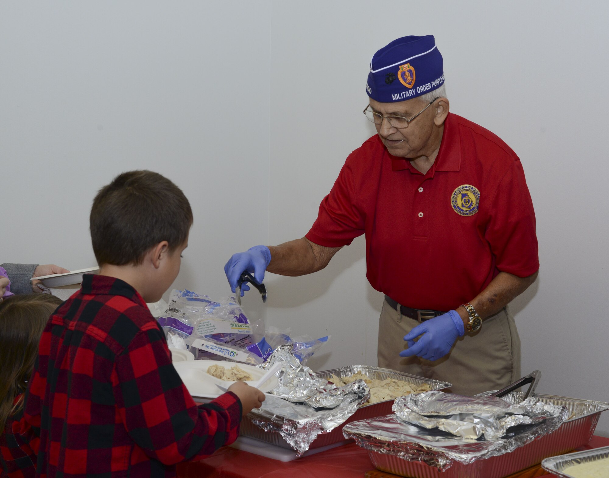 Wilson Morgan, purple heart recipient and volunteer, serves turkey during a holiday party, Dec. 15, 2017, at Moody Air Force Base, Ga. The Airman and Family Readiness Center hosted the event for families of deployed or remote-tour Airmen, and families enrolled in the Exceptional Family Member Program. During the party, families enjoyed a turkey dinner, played games, made arts and crafts for their loved ones and shared a special moment with Santa Claus. (U.S. Air Force photo by Senior Airman Lauren M. Sprunk)