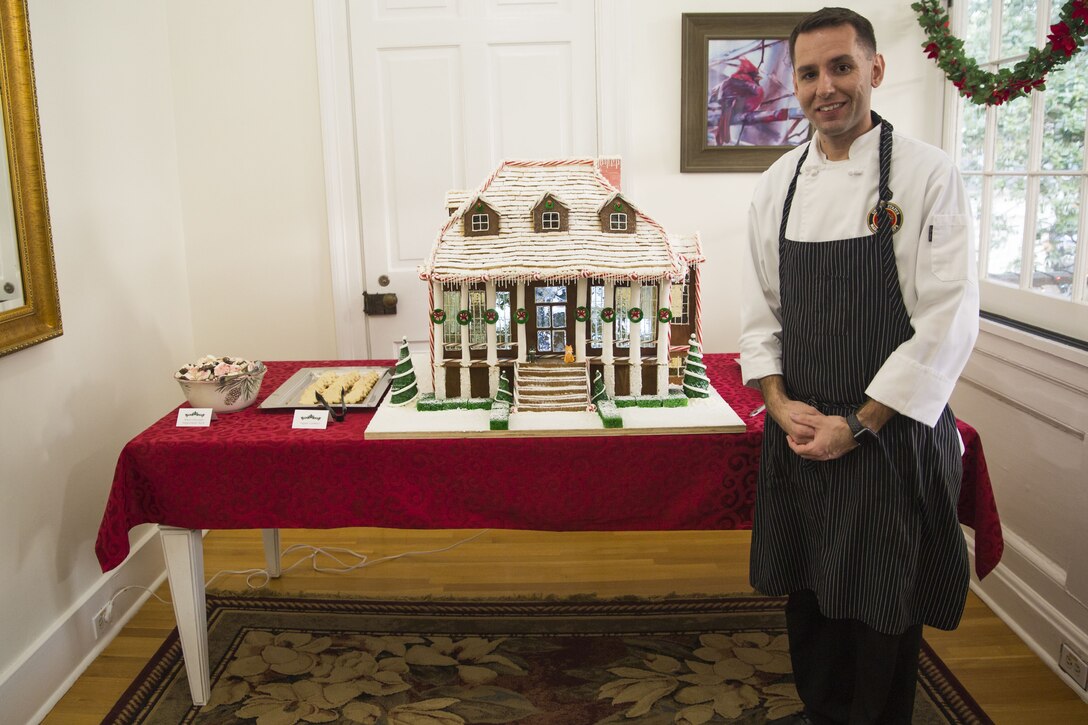 Staff Sgt. Anthony Maietta, an enlisted aide to Lt. Gen. Rex C. McMillian, commander of Marine Forces Reserve and Marine Forces North, poses with his homemade gingerbread house, created for an annual Christmas party hosted by McMillian, Dec. 16, 2017.