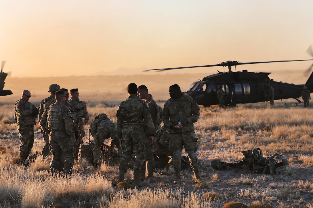 Army pilots, crew chiefs and soldiers discus the plan for a day and night aerial gunnery and air assault training.